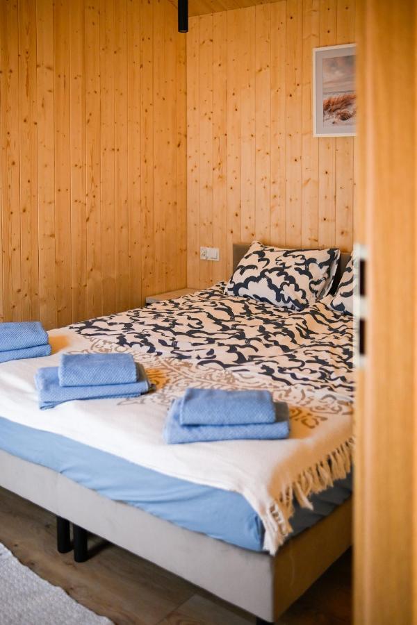 Sypialnia z wzorzystą pościelą w stylu boho i drewnianymi ścianami